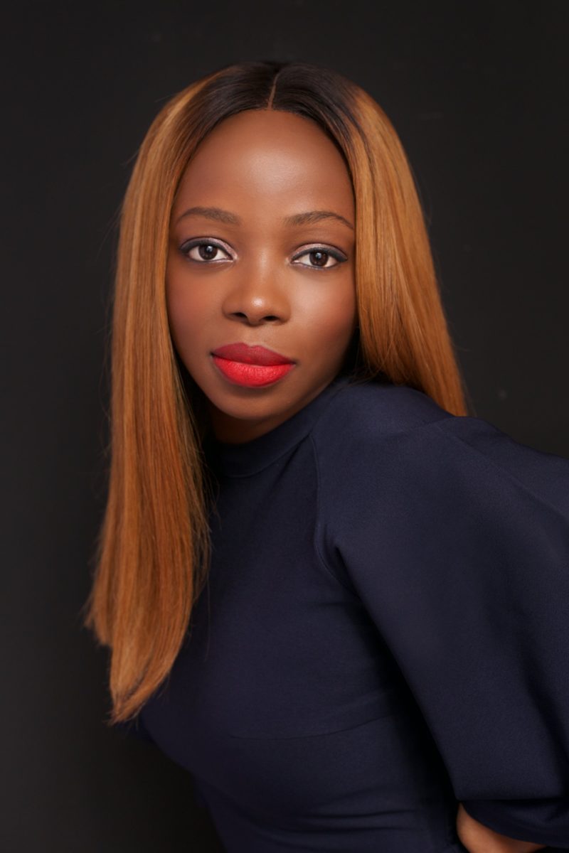 Folayemi Agusto, studio headshot in a navy top against a dark background